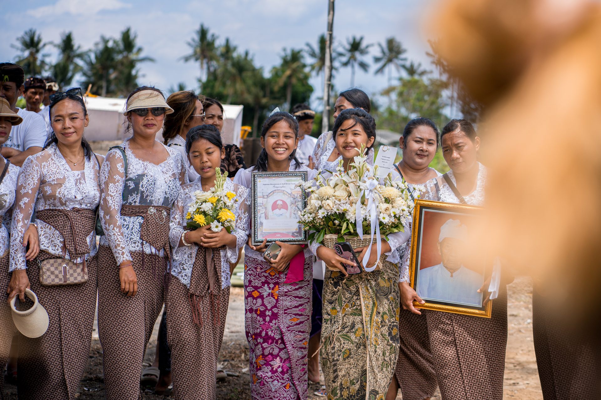 Jeunes femmes portant le portrait du défunt et des bouquets de fleurs blanches, Bali
