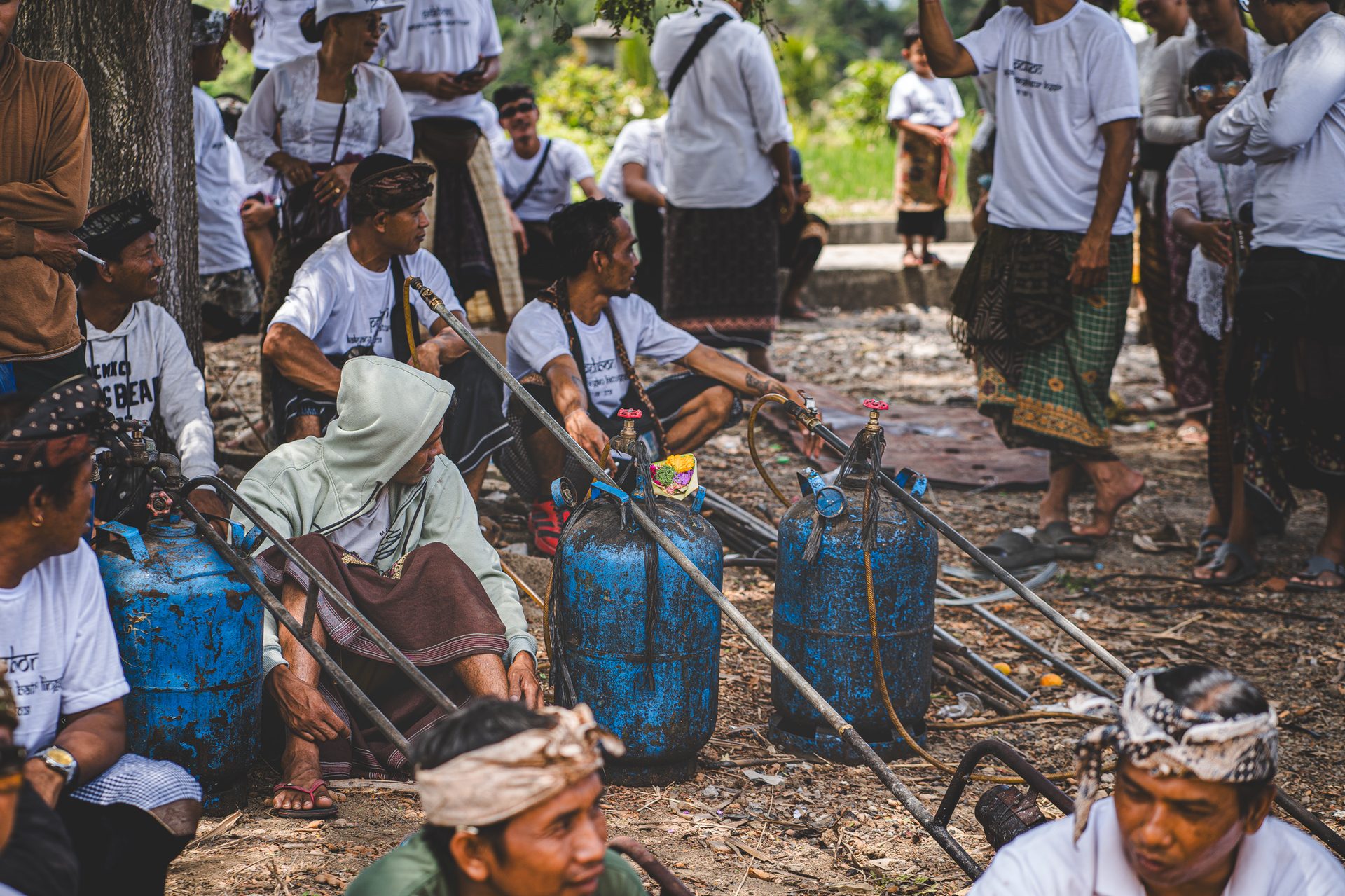 Hommes assis près des bonbonnes de gaz et torches destinées à l'embrasement, Bali