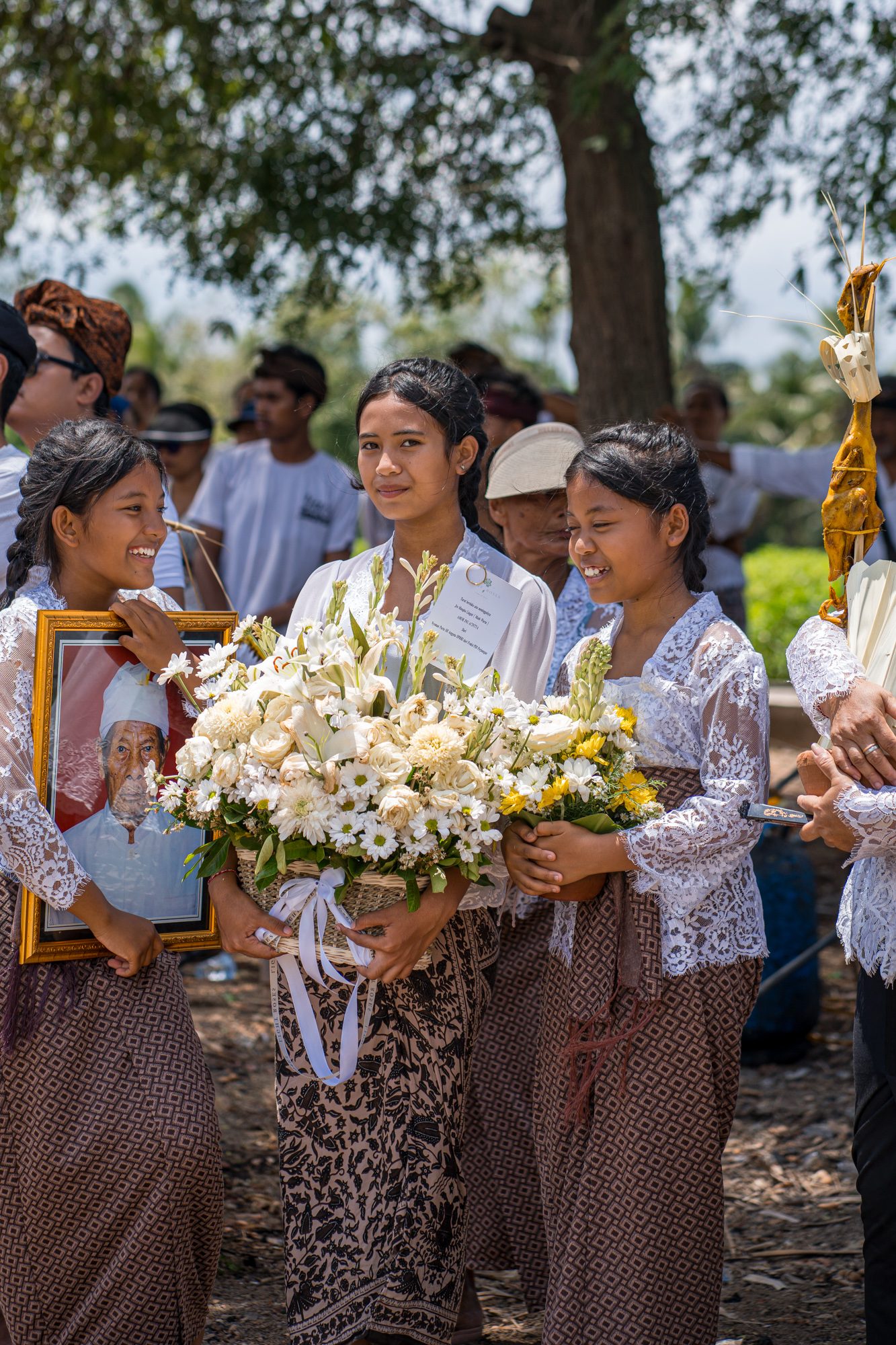 Fillettes souriantes portant fleurs et portrait du défunt pendant la procession, Bali