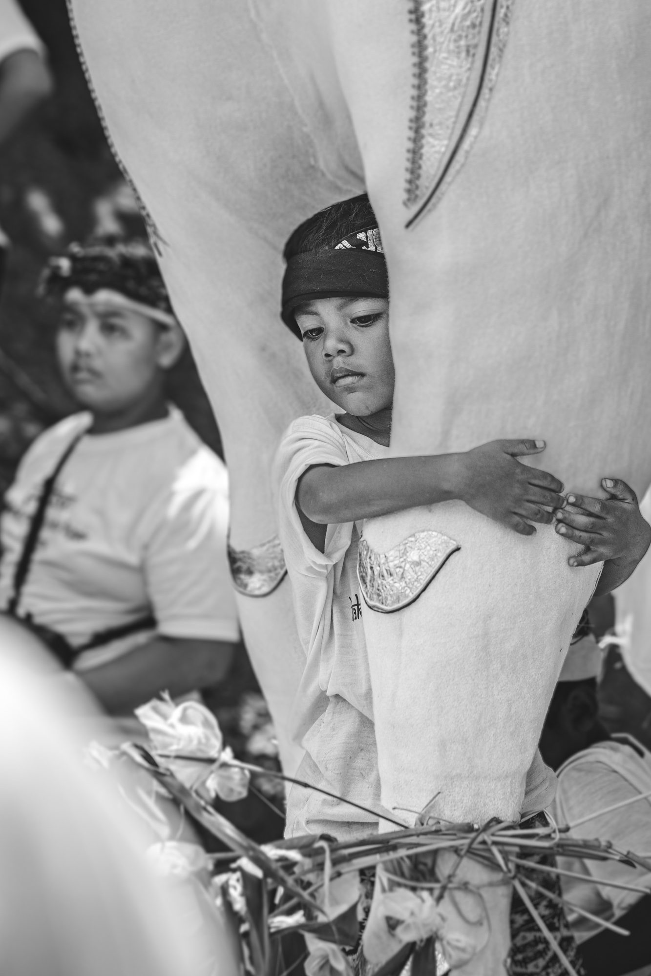 Enfant agrippé à la patte du petulangan, portrait noir et blanc, Bali