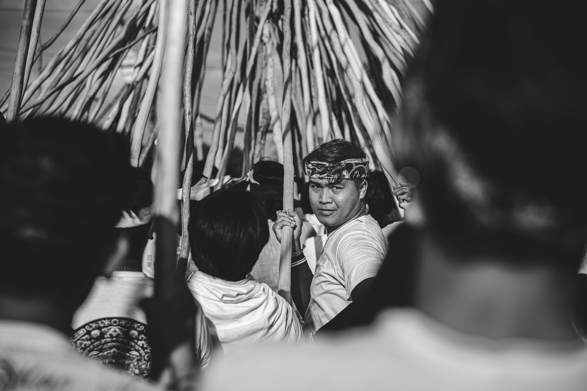 Homme regardant l'objectif sous l'enchevêtrement de bâtons de pulet, Mekotek, Munggu, Bali