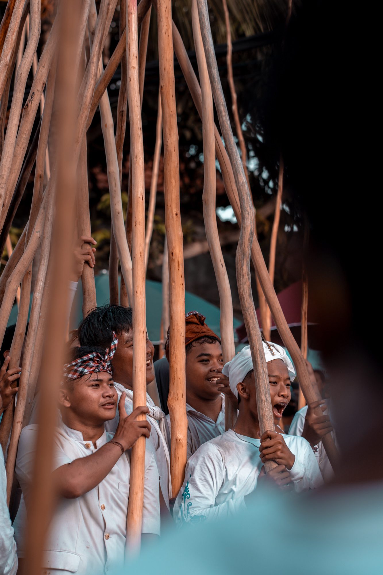 Jeunes hommes riant en tenant leurs bâtons de pulet dans la lumière du soir, Munggu, Bali