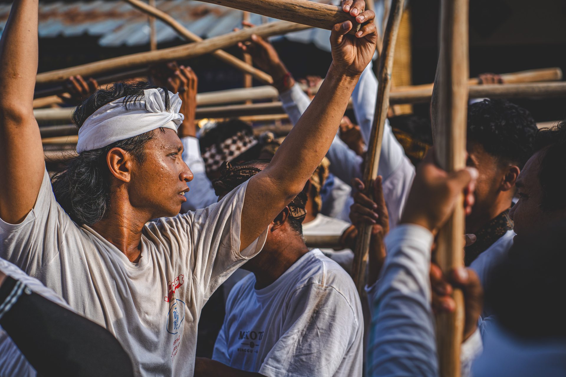 Homme brandissant son bâton de pulet au-dessus de la foule pendant le Mekotek, Munggu, Bali