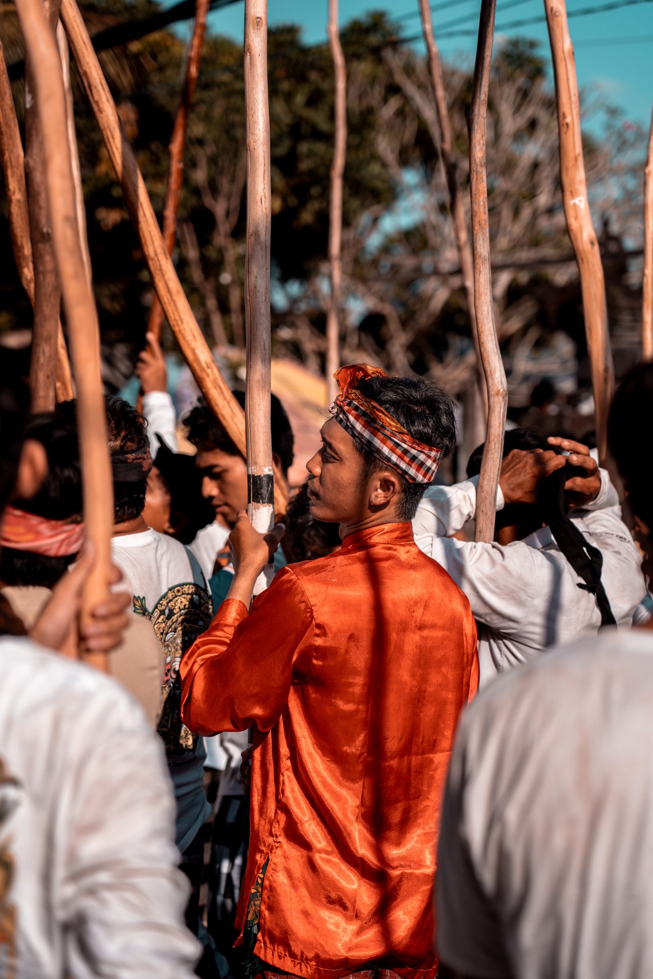 Homme en habit de cérémonie orange tenant un bâton de pulet, Mekotek, Munggu, Bali